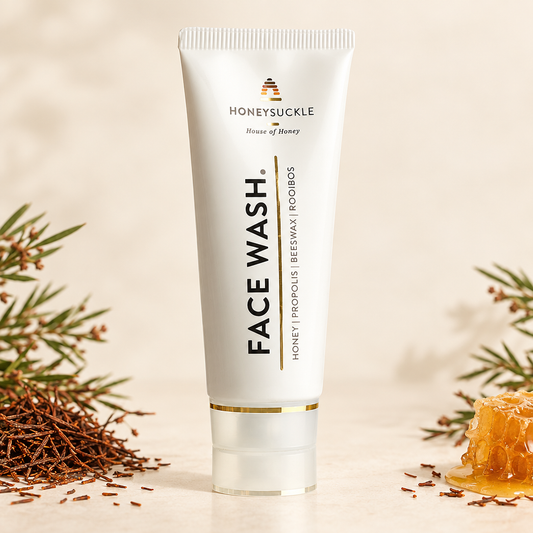 Honeysuckle Face Wash 100ml displayed upright in a warm ivory setting with rooibos and honey