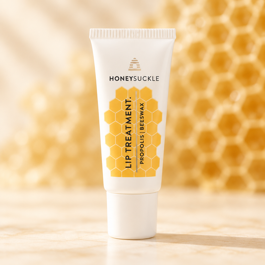 Honeysuckle Propolis Lip Treatment 10ml tube with yellow honeycomb label on a warm ivory surface