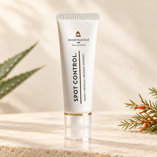 Honeysuckle Spot Control 25ml white squeeze tube with vertical label and gold band on warm ivory stone