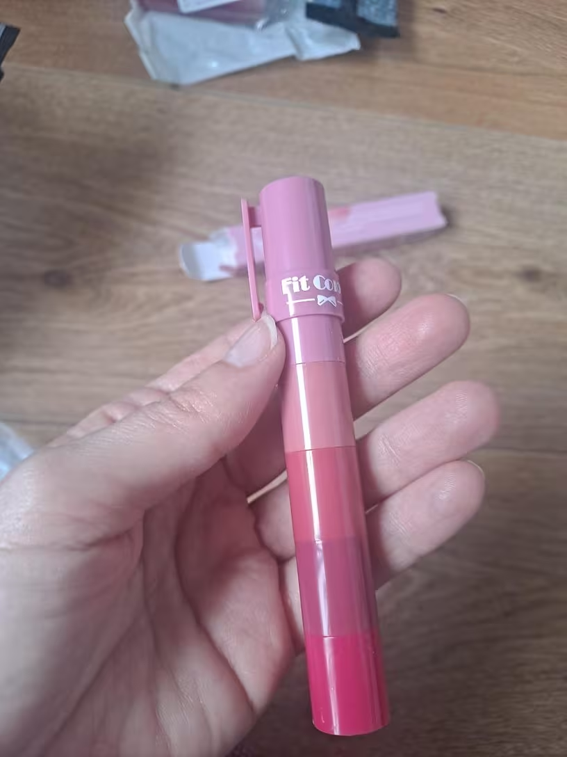 Hand holding 5-in-1 lipstick pen showing gradient barrel detail